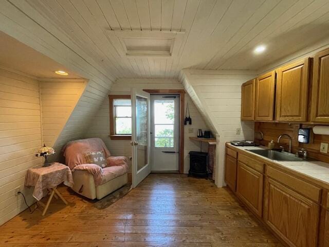 interior space featuring wood walls, wooden ceiling, vaulted ceiling, light hardwood / wood-style flooring, and sink