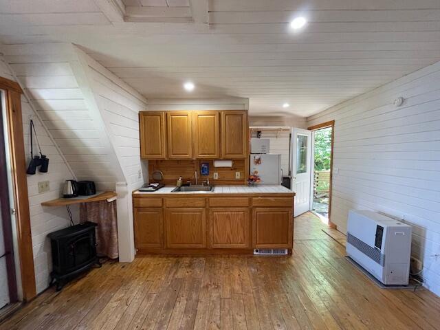 kitchen featuring heating unit, wood-type flooring, sink, and a wood stove