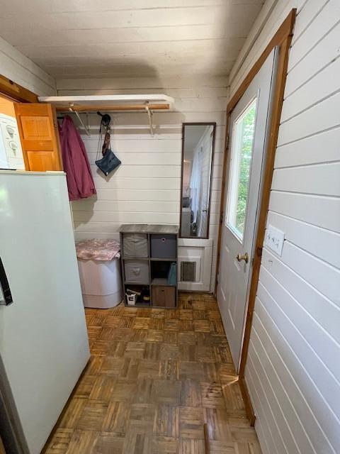 mudroom with wood walls and dark parquet floors