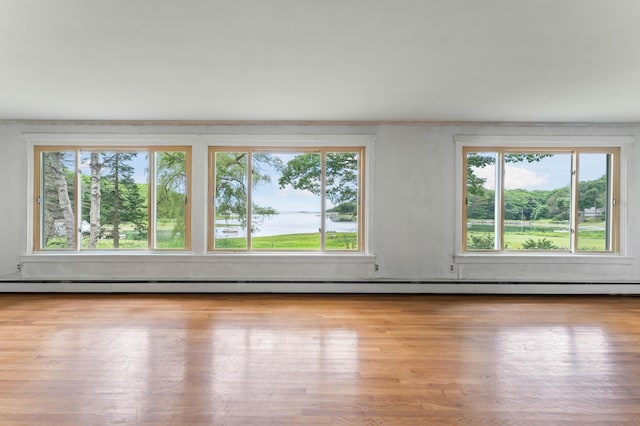 empty room featuring a baseboard heating unit and wood finished floors