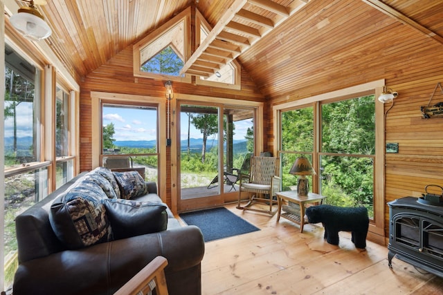 sunroom with a wood stove, wooden ceiling, and lofted ceiling