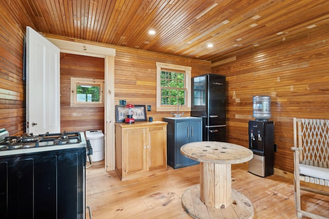 kitchen featuring light wood-type flooring, blue cabinets, white gas stove, and wood walls