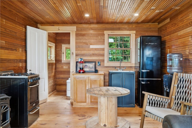 kitchen with blue cabinetry, high end stainless steel range oven, black fridge, wood walls, and a kitchen island