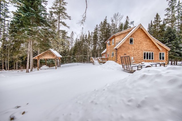 snow covered back of property featuring a gazebo and a deck