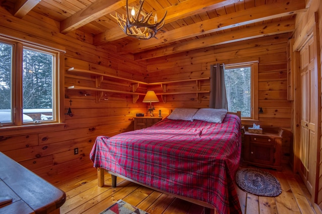 bedroom with beamed ceiling, wooden ceiling, multiple windows, and light hardwood / wood-style flooring