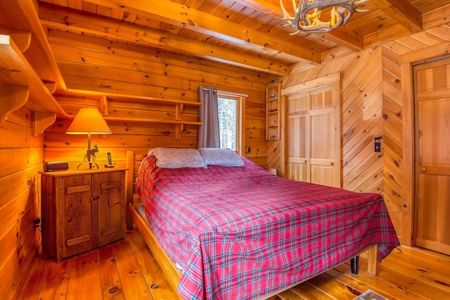 bedroom with wooden walls, wooden ceiling, beam ceiling, and light hardwood / wood-style flooring