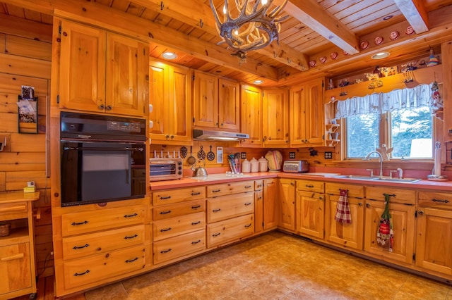 kitchen with beamed ceiling, sink, black oven, and wood ceiling