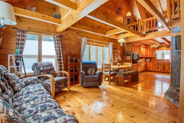 living room with beamed ceiling, a wealth of natural light, light hardwood / wood-style floors, and wood walls