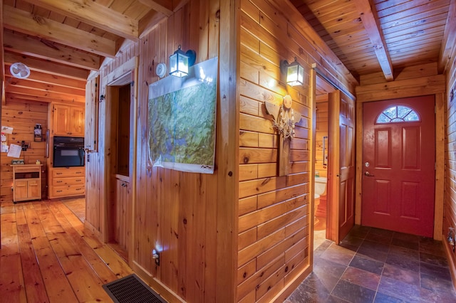 corridor featuring beamed ceiling, wood ceiling, and wooden walls