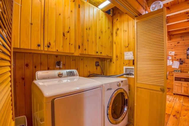 washroom featuring cabinets, independent washer and dryer, and wood walls