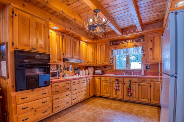 kitchen featuring black oven, beamed ceiling, hanging light fixtures, white fridge, and wood ceiling