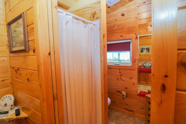 bathroom with toilet, wood walls, and vaulted ceiling