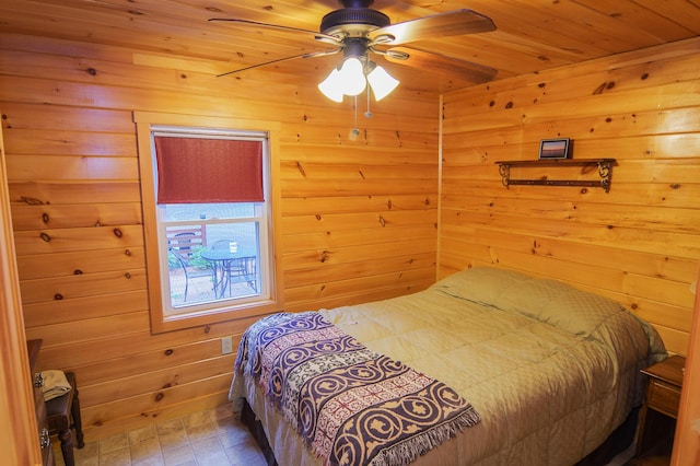 bedroom with ceiling fan and wood walls