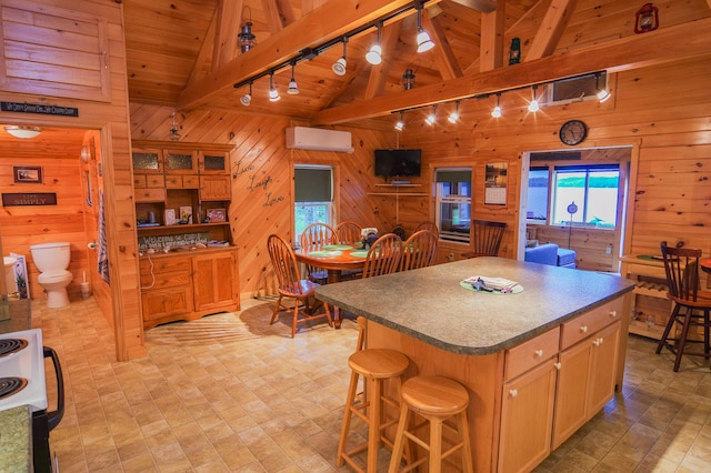 kitchen with a center island, beam ceiling, wooden walls, a wall mounted air conditioner, and rail lighting