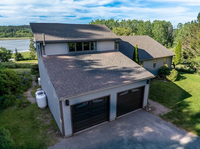 exterior space with a water view, a garage, and a front lawn