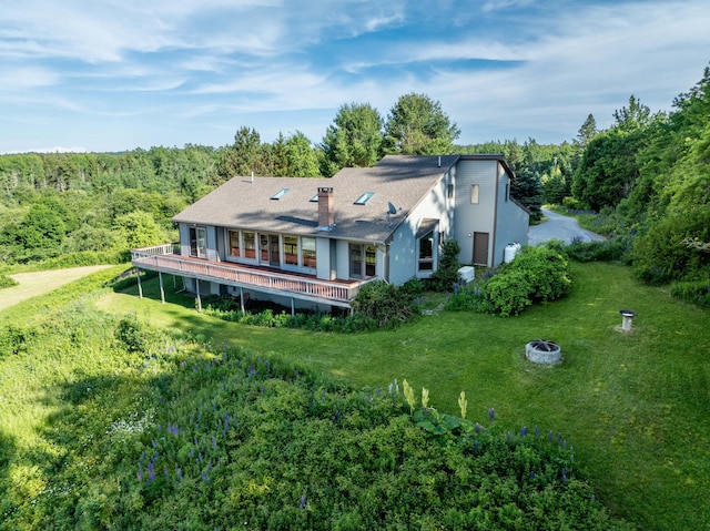 back of house featuring a deck, an outdoor fire pit, and a lawn