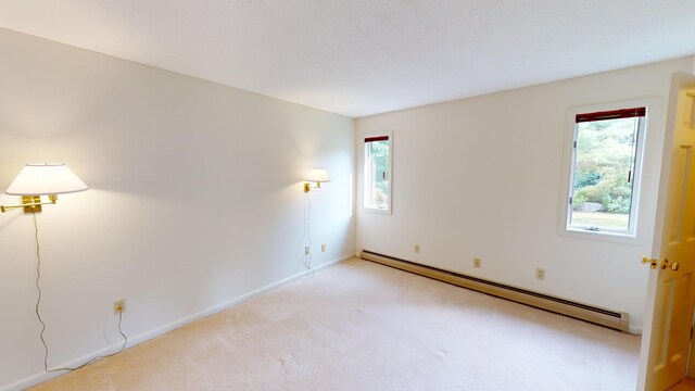 carpeted spare room with a baseboard radiator