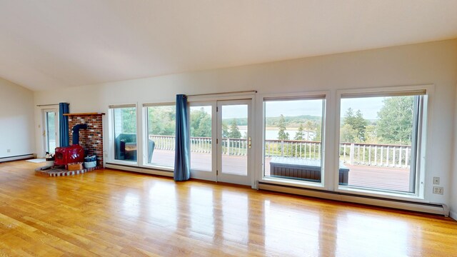 doorway to outside with vaulted ceiling, a baseboard heating unit, and light wood-type flooring