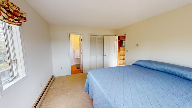 carpeted bedroom with a baseboard radiator and ensuite bath