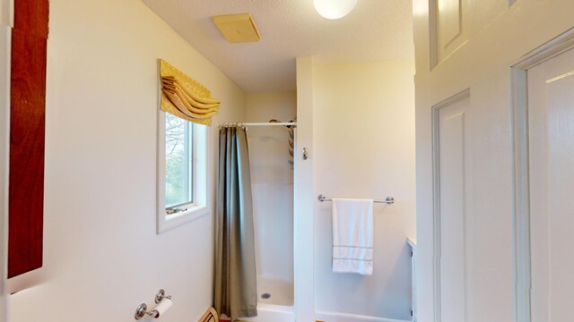 bathroom with curtained shower and a textured ceiling