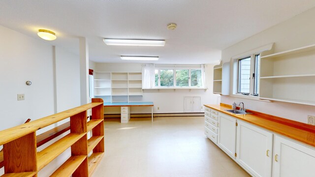 kitchen with wooden counters, sink, and white cabinets