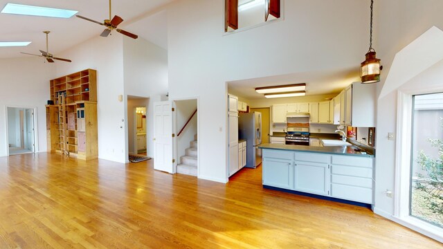 kitchen featuring sink, a skylight, hanging light fixtures, appliances with stainless steel finishes, and white cabinets