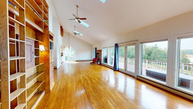 unfurnished living room featuring a healthy amount of sunlight, a baseboard heating unit, light wood-type flooring, and a skylight