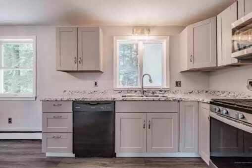 kitchen with sink, a baseboard radiator, black dishwasher, stainless steel stove, and white cabinetry