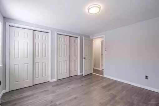 unfurnished bedroom featuring two closets and hardwood / wood-style flooring