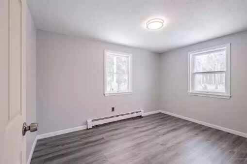 spare room with dark hardwood / wood-style floors and a baseboard heating unit