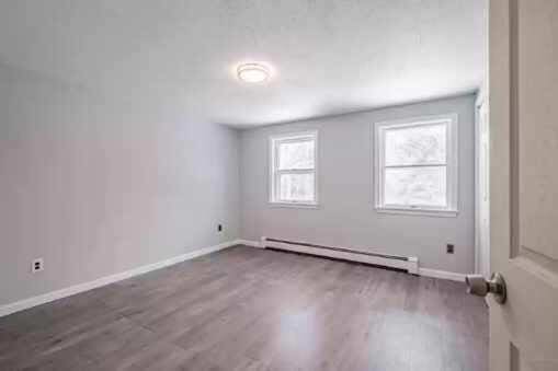 spare room with hardwood / wood-style floors and a baseboard heating unit