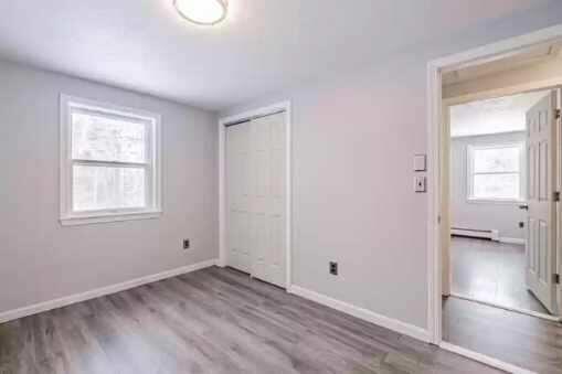 unfurnished bedroom featuring a closet, light wood-type flooring, and a baseboard heating unit