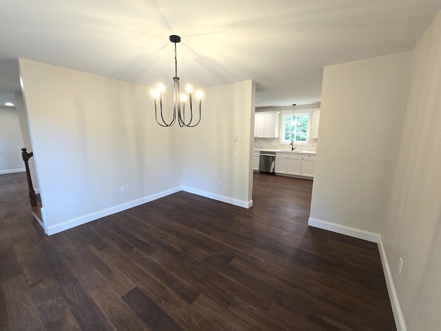 unfurnished dining area featuring dark wood-type flooring, a sink, baseboards, and an inviting chandelier