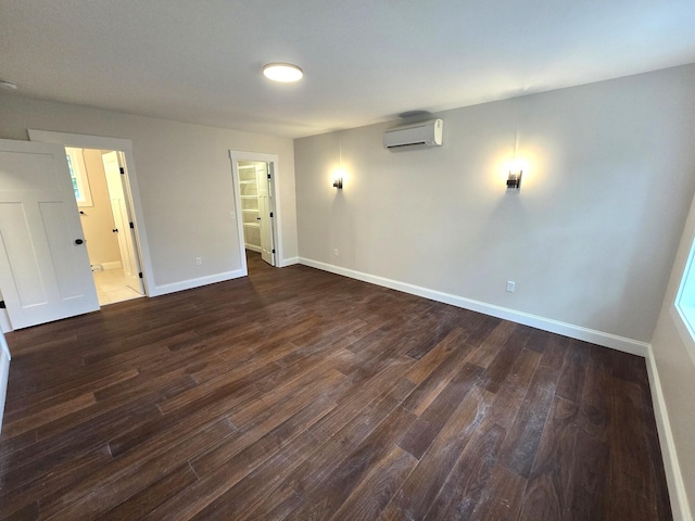 unfurnished room with baseboards, dark wood-type flooring, and an AC wall unit