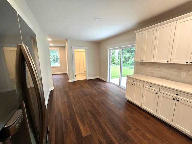 kitchen with dark wood-style floors, baseboards, decorative backsplash, and a wealth of natural light