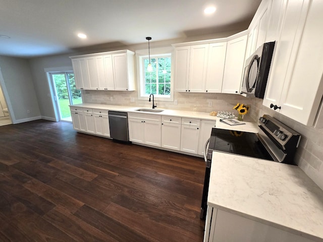 kitchen with dark wood-style floors, appliances with stainless steel finishes, a sink, white cabinetry, and backsplash