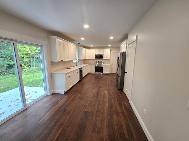 kitchen with dark wood-style flooring, appliances with stainless steel finishes, light countertops, recessed lighting, and baseboards