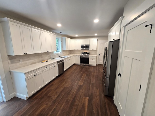 kitchen featuring stainless steel appliances, a sink, light countertops, tasteful backsplash, and dark wood finished floors