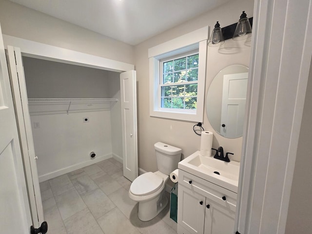 bathroom with baseboards, vanity, toilet, and a spacious closet