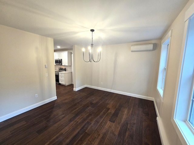 unfurnished dining area with baseboards, dark wood finished floors, a wall unit AC, an inviting chandelier, and a wealth of natural light