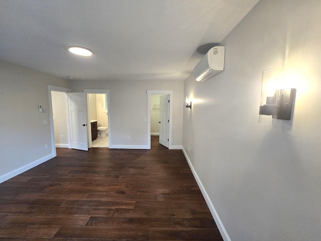 unfurnished room with dark wood-style floors, an AC wall unit, and baseboards