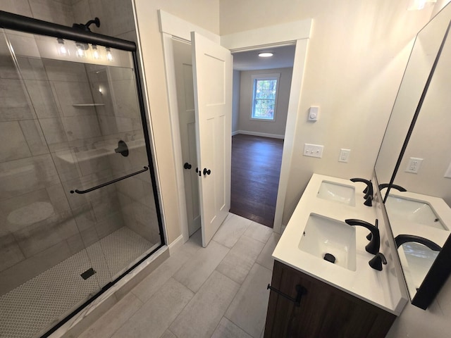 full bath with double vanity, a stall shower, and a sink