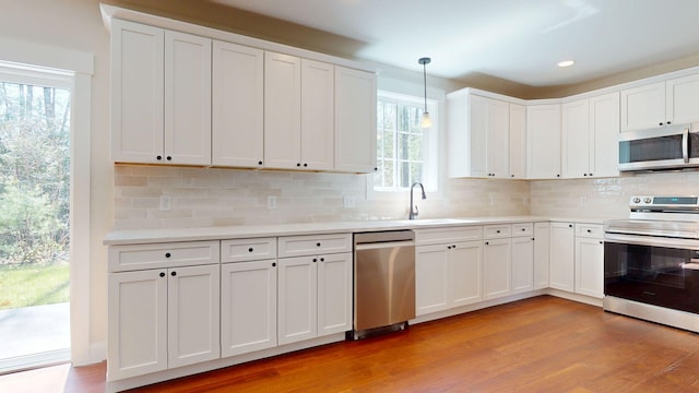 12 Country Dr, Old Orchard Beach, ME 04064 - kitchen featuring appliances with stainless steel finishes, a sink, light wood-type flooring, decorative backsplash, and healthy amount of natural light