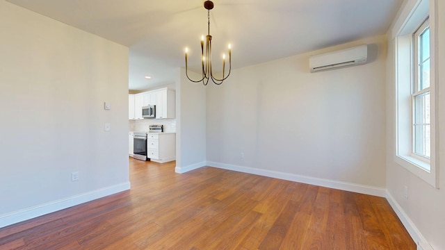 12 Country Dr, Old Orchard Beach, ME 04064 - unfurnished dining area with a wall unit AC, a chandelier, wood finished floors, and baseboards