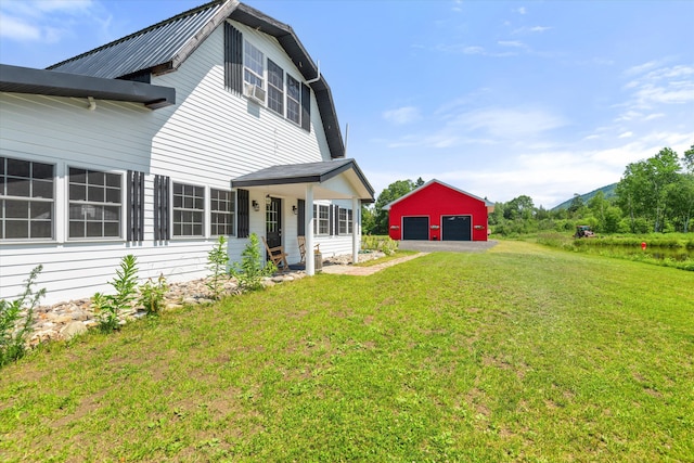 back of house featuring a garage, a lawn, an outdoor structure, and covered porch