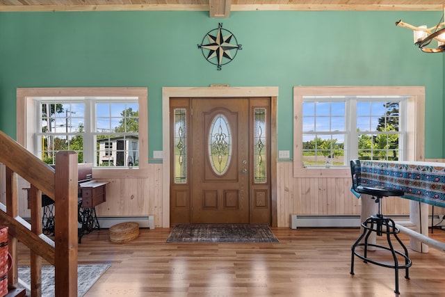 entrance foyer featuring an inviting chandelier, a baseboard radiator, beam ceiling, and hardwood / wood-style floors