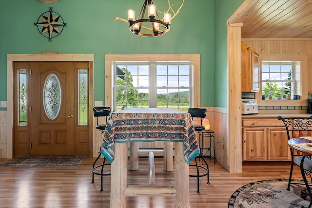 entryway featuring light hardwood / wood-style flooring, wood walls, and an inviting chandelier