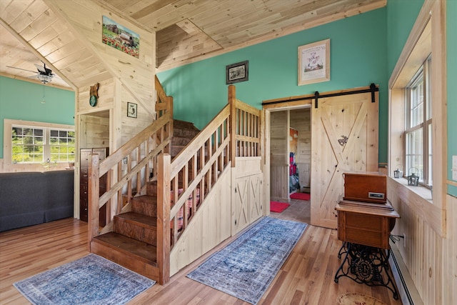 stairs featuring wooden ceiling, baseboard heating, ceiling fan, a barn door, and hardwood / wood-style floors