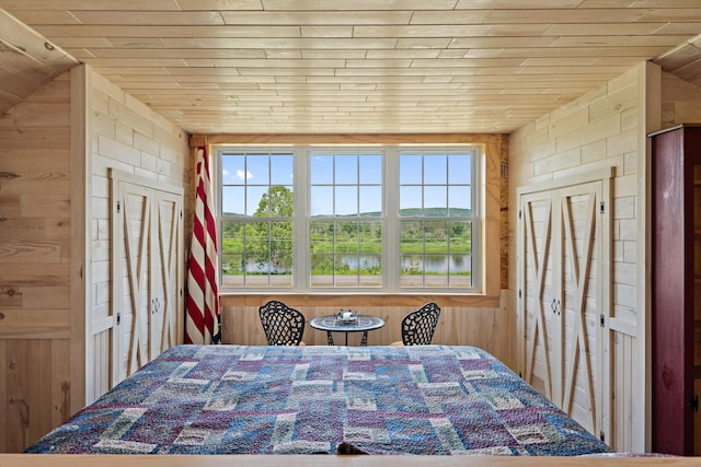 unfurnished bedroom featuring wood ceiling, a water view, and wood walls