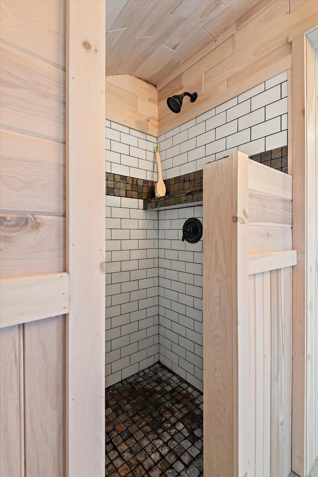 bathroom with wood ceiling, wood walls, and tiled shower